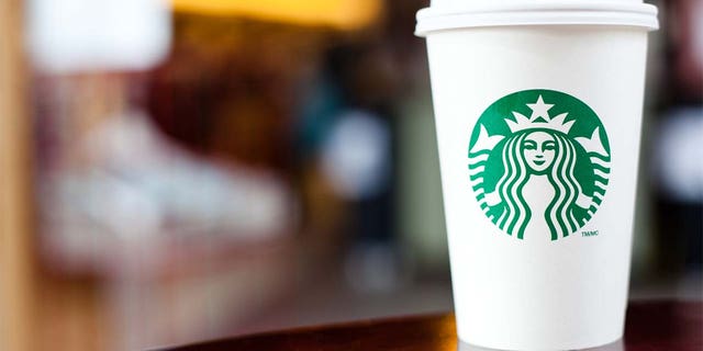 "Halifax, Nova Scotia, Anada - Sep 18, 2011: Grande Starbucks goes for a cup sitting at a table.  Starbucks is a hugely popular international coffee shop franchise with over 15,000 locations in 50 countries"