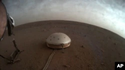 In this undated image made available by NASA on Thursday, July 22, 2021, clouds drift over the dome-covered SEIS seismometer of the InSight lander on Mars.