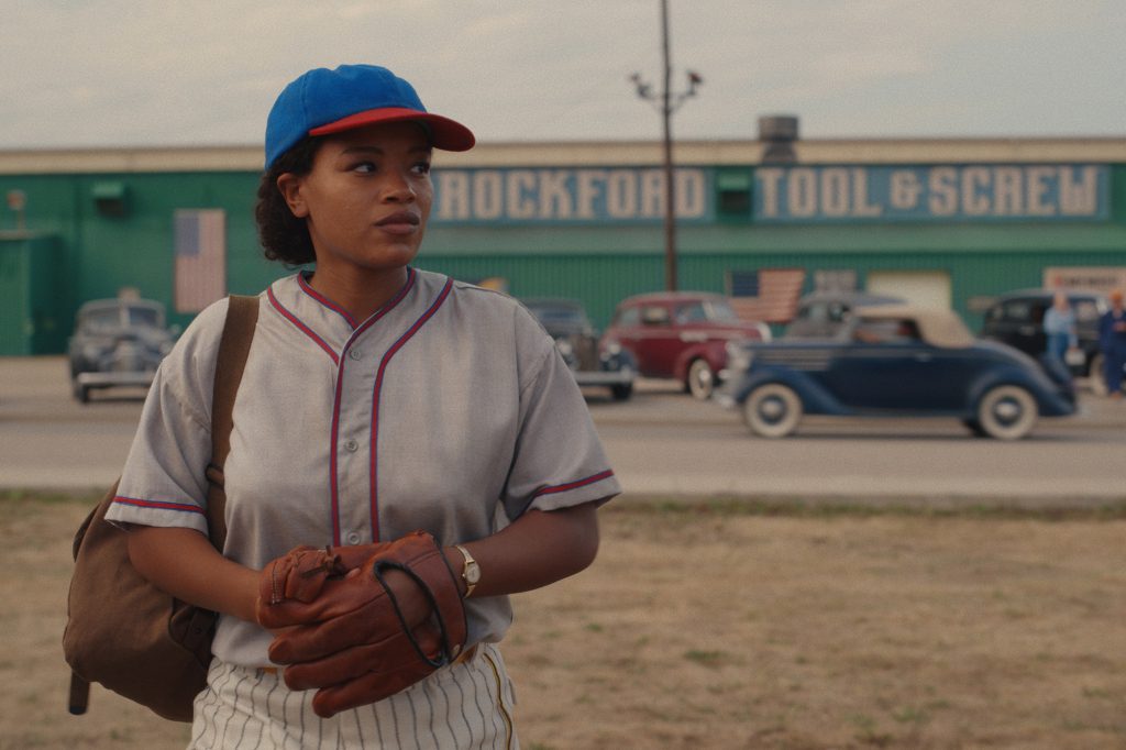 Max (Shanty Adams) standing in a bunker holding a baseball glove "a league of their own." 