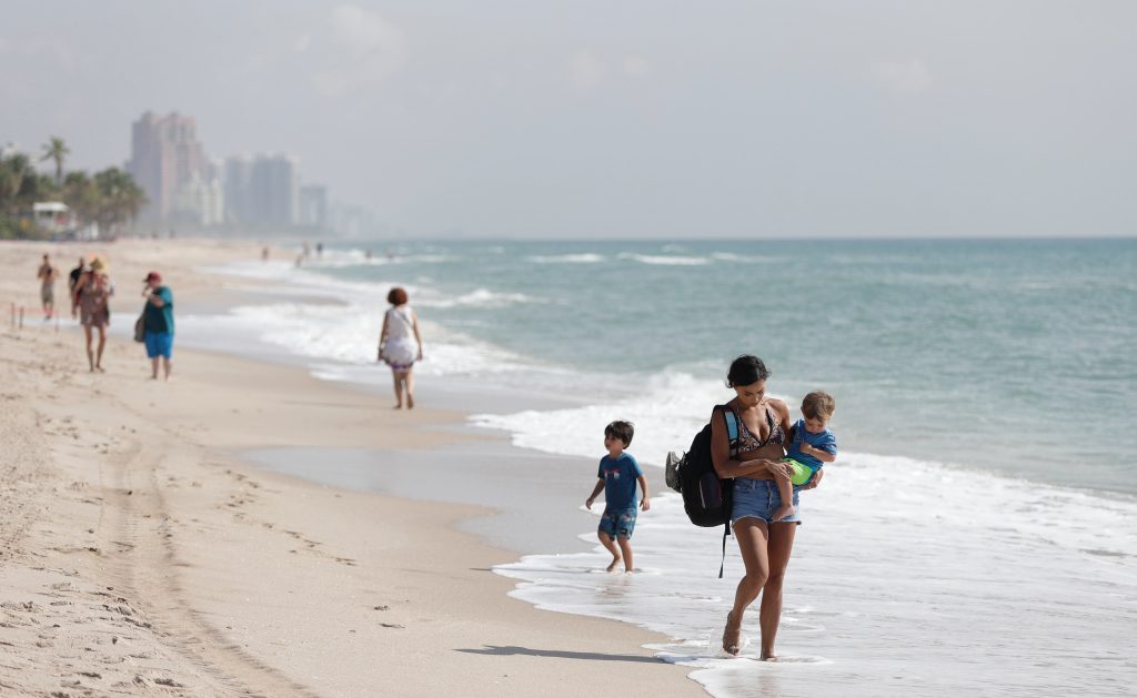 Beach-goers walk along the shoreline in Fort Lauderdale, Florida.